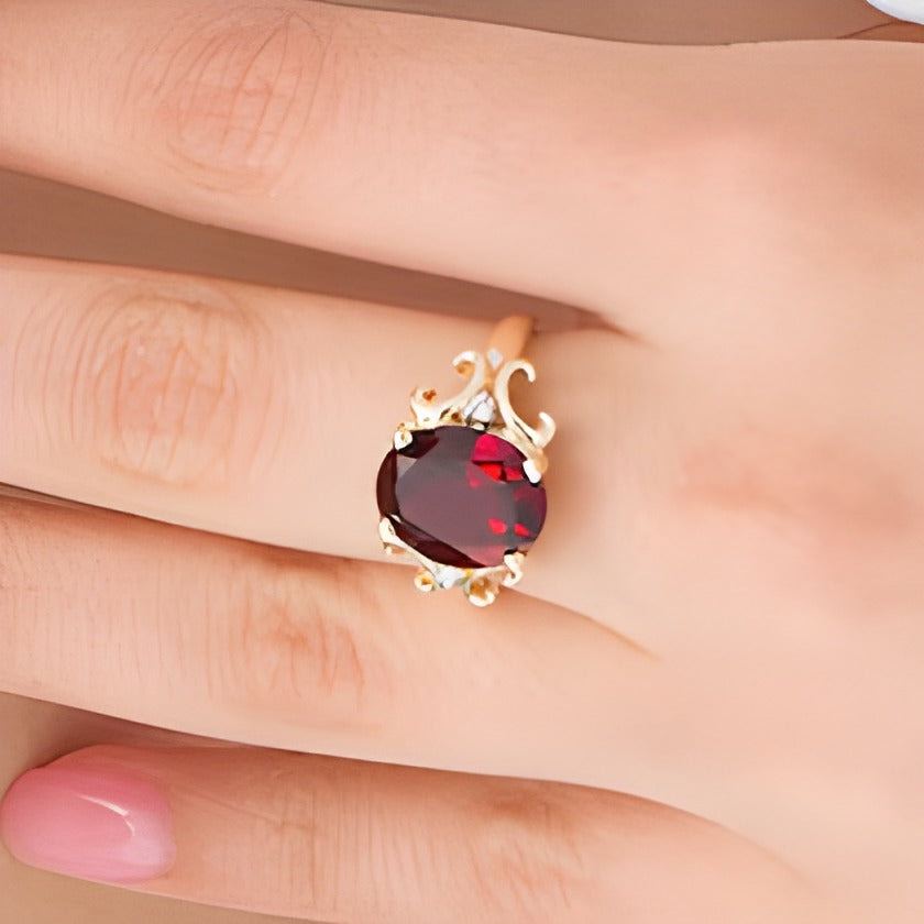 Oval Garnet and 0.05 CT. TW Diamond Scroll Frame Ring in 10K Gold